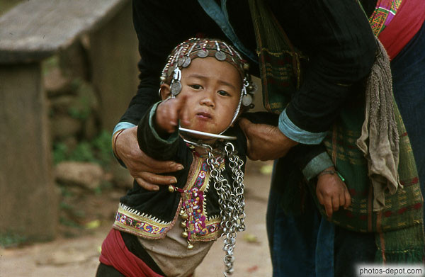 enfant tête couverte d'un pendentif de pièces, montre du doigt photo